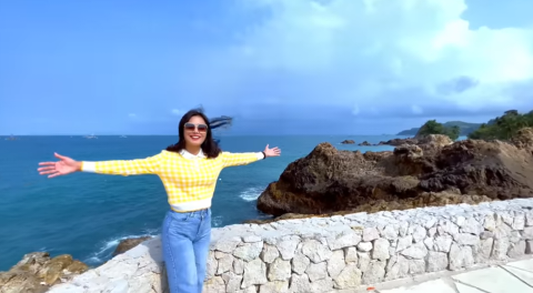 a woman standing on a stone wall with her arms outstretched